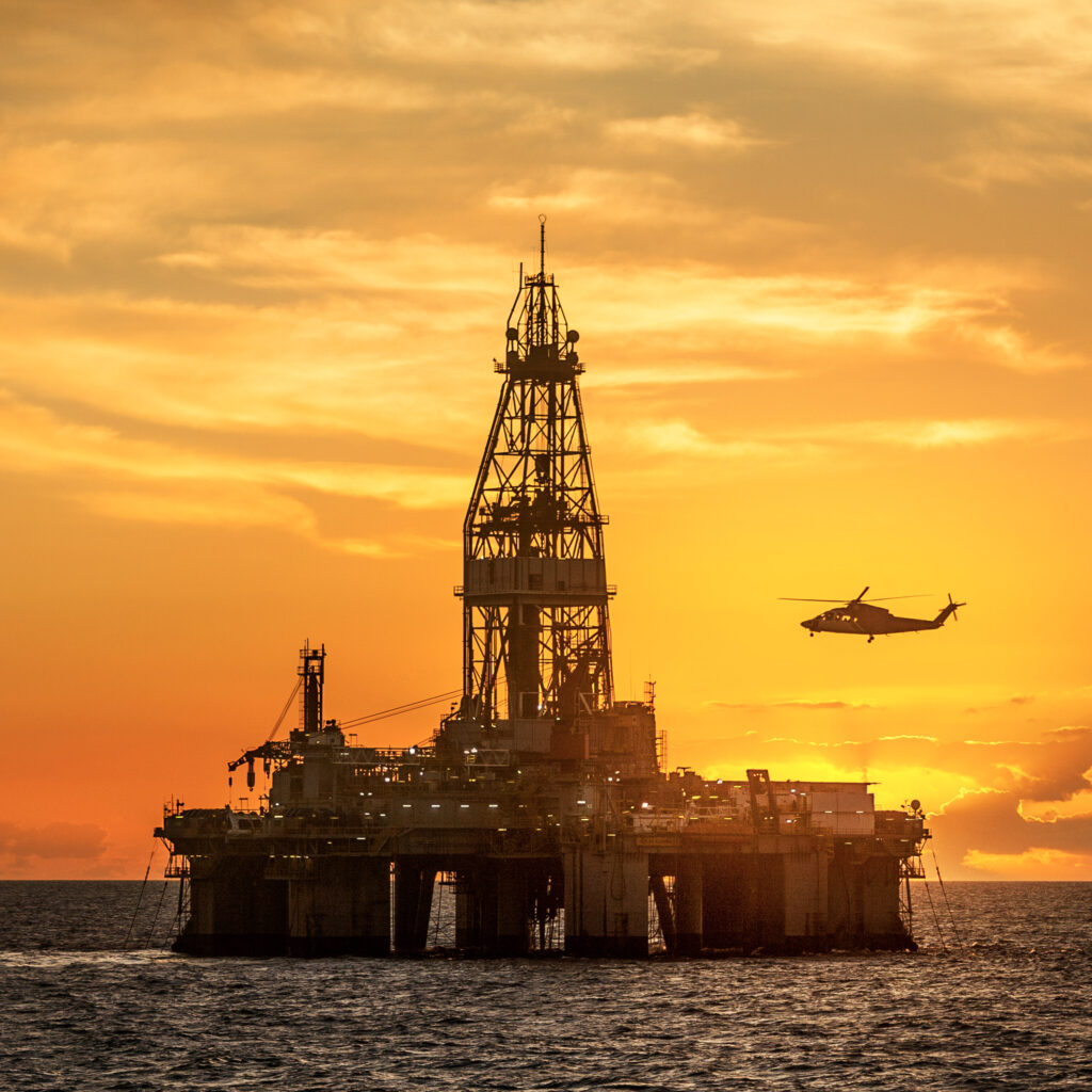 helicopter-flying-over-oil-rig-in-sea-against-sky